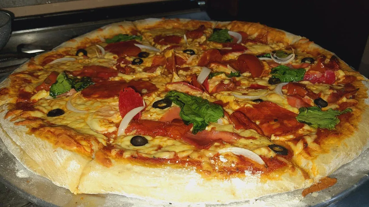 Pizza artesanal jamón, peperoni, tocino y Tomate/albahaca